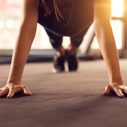 Close up woman hand doing push ups exercise in a gym in morning, sunlight effect.