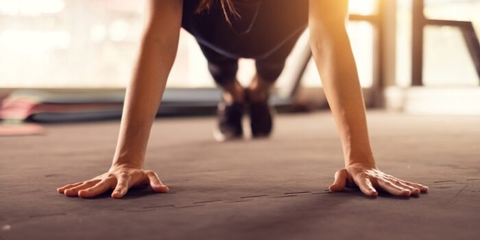 Close up woman hand doing push ups exercise in a gym in morning, sunlight effect.