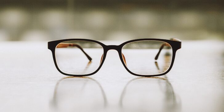 Pink classic eye glasses on wooden table.