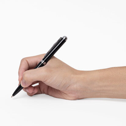 Hand holding pen writing on white background, closeup.